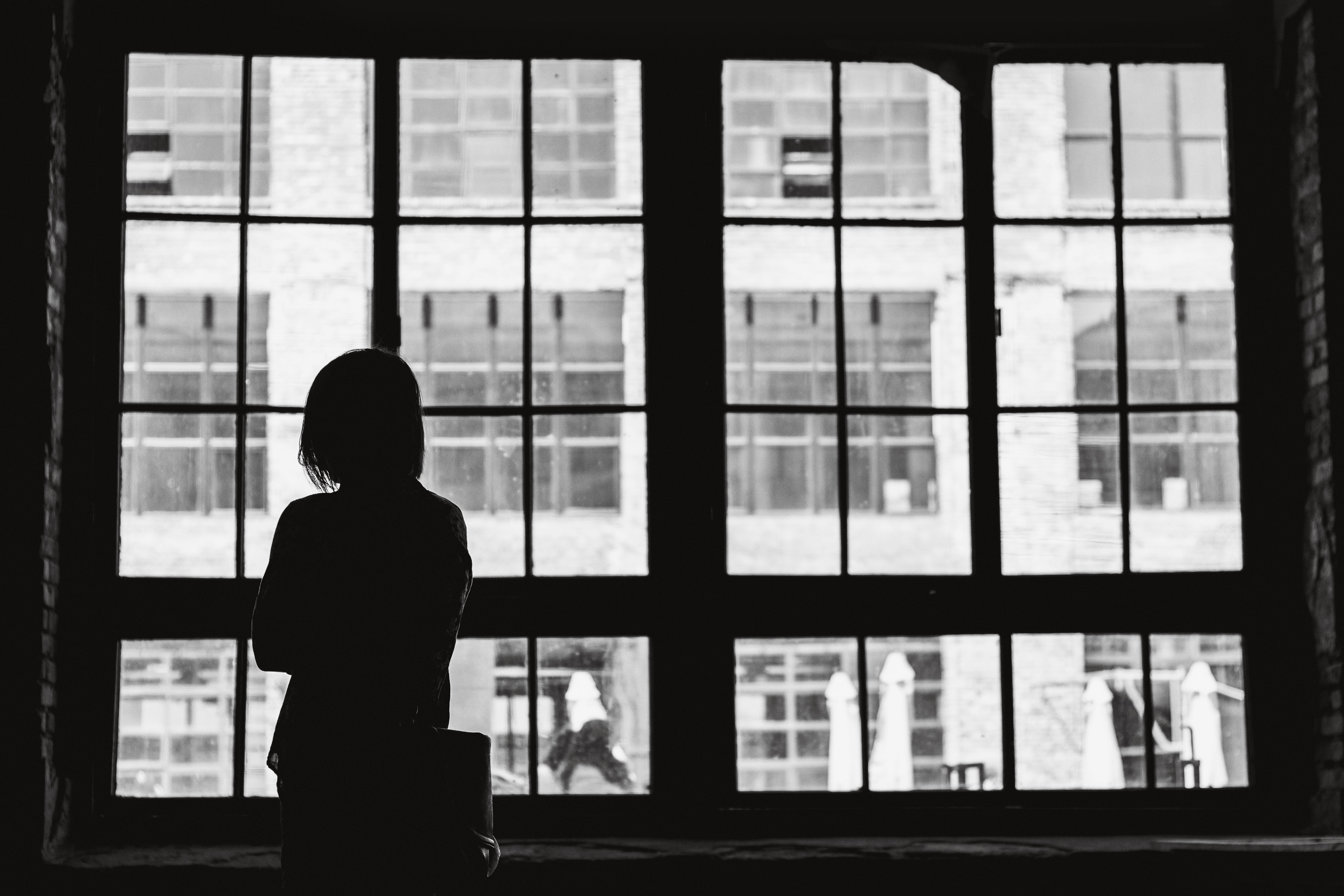 Silhouette of a person looking out of a window